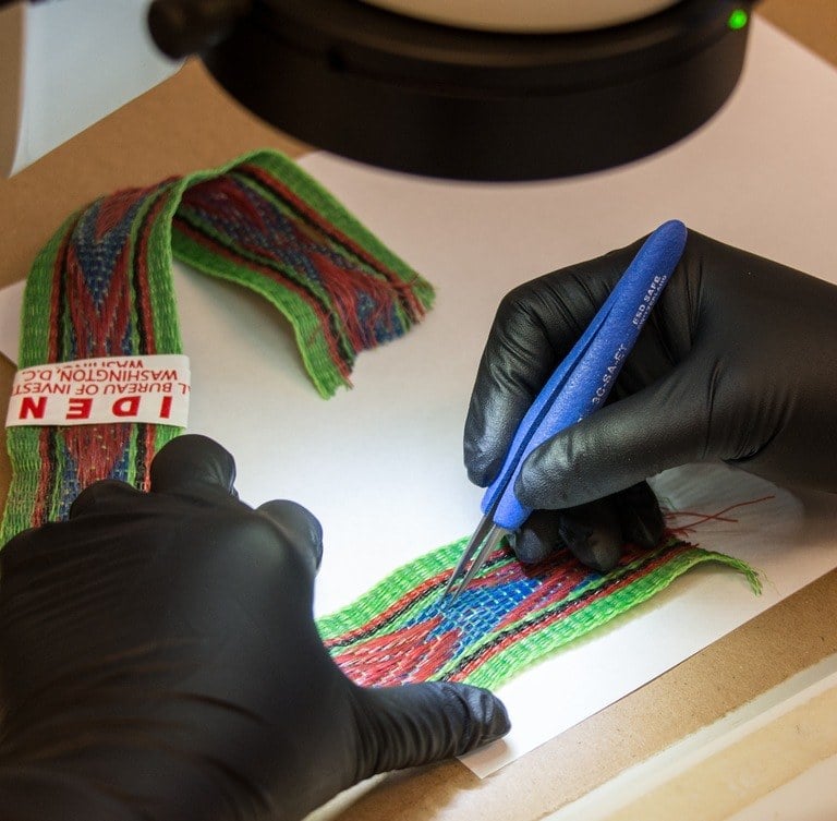 An analyst looks for patterns on a piece of fabric.
